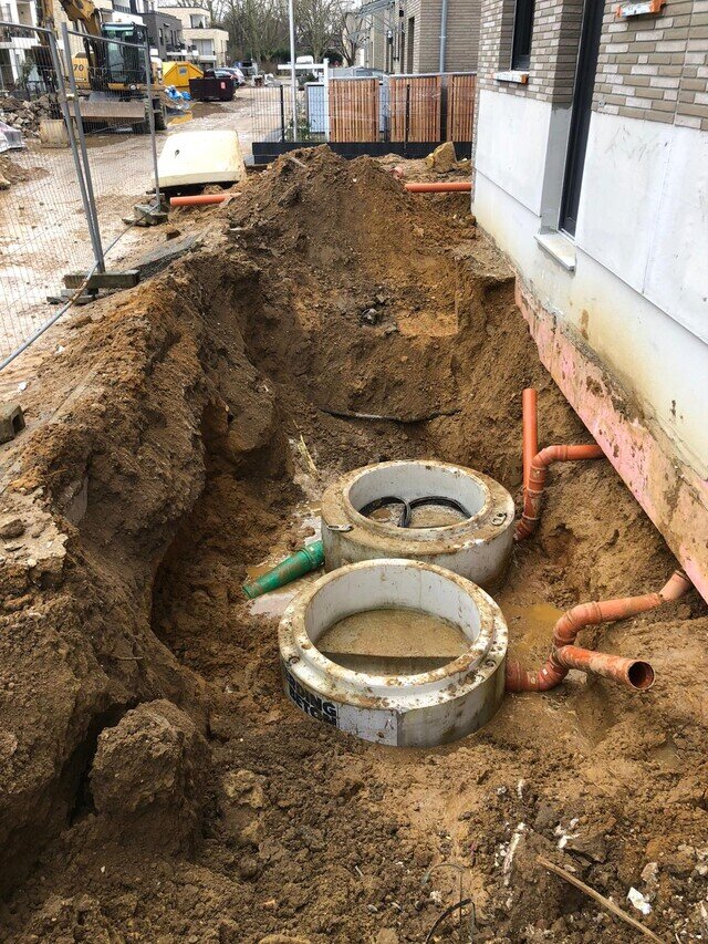 Freigelegte Rohre und zwei Betonschächte neben einem Wohnhaus